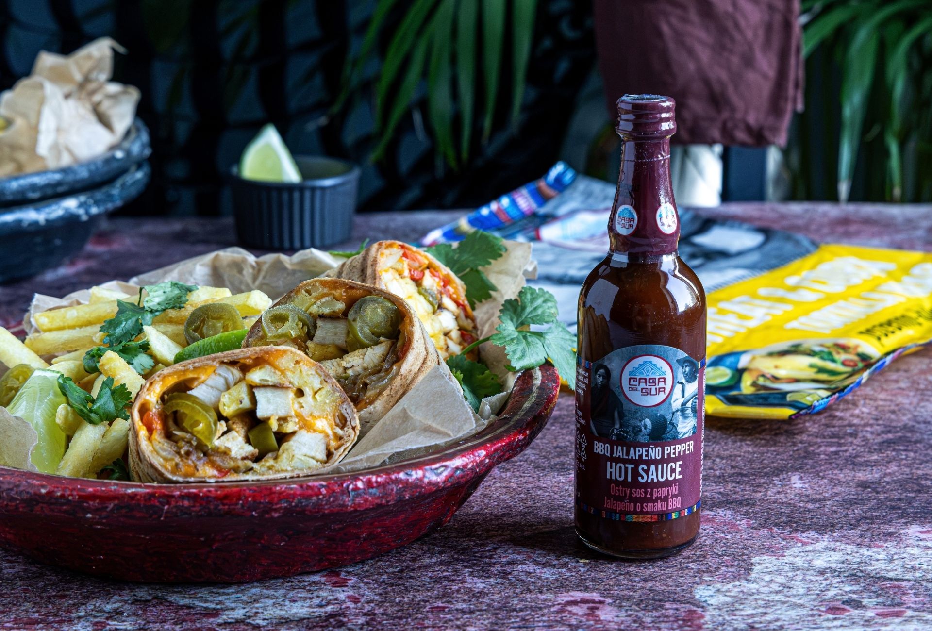 Przekrojony french taco z grillowanym kurczakiem, jalapeño i frytkami w misce, podany obok butelki sosu BBQ Jalapeño Pepper marki Casa del Sur.
